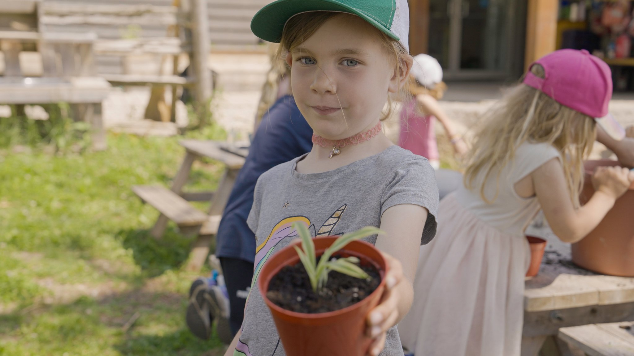 Child presenting a potted native plant — outdoor learning at Kimbercote